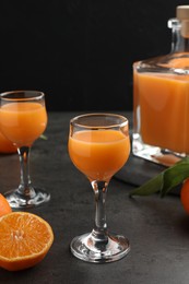 Delicious tangerine liqueur and fresh fruits on grey table