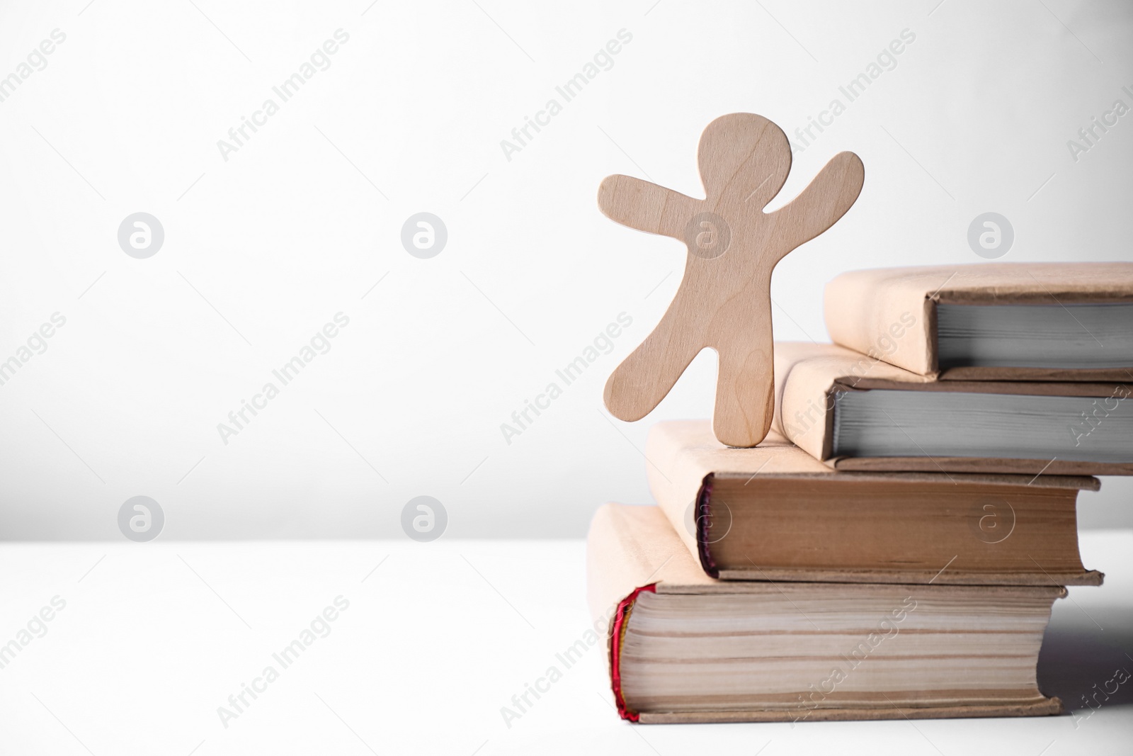 Photo of Figure of man climbing book stairs against light background, space for text