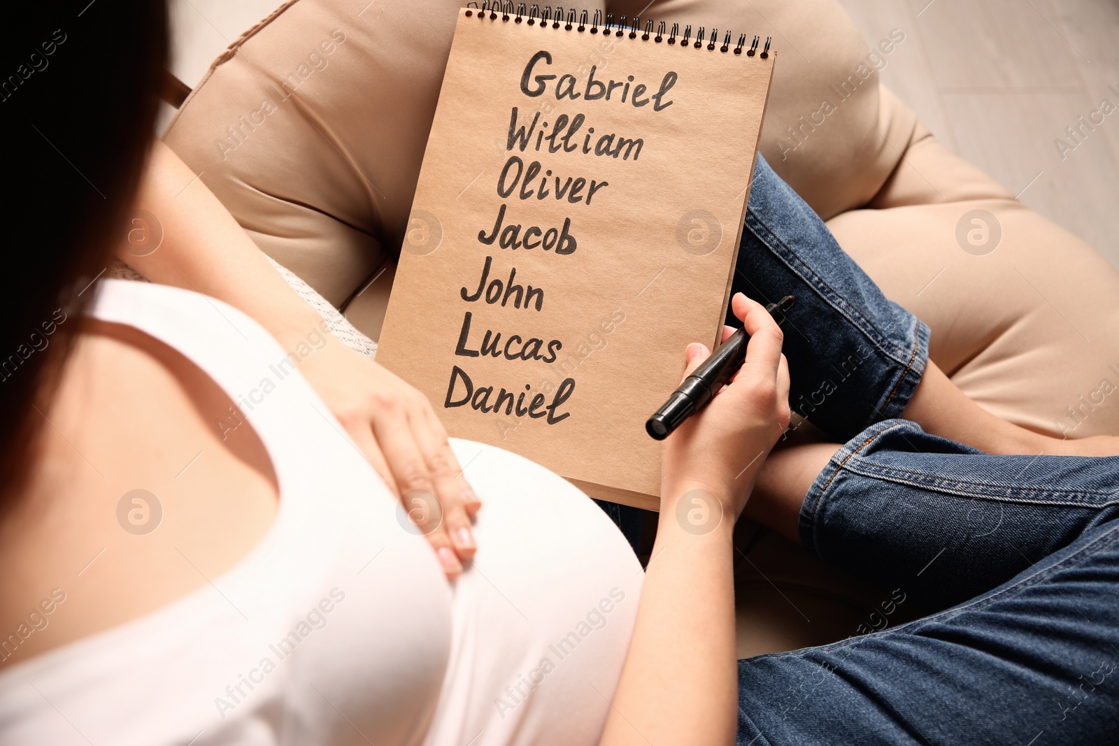 Photo of Pregnant woman with baby names list sitting in armchair, closeup