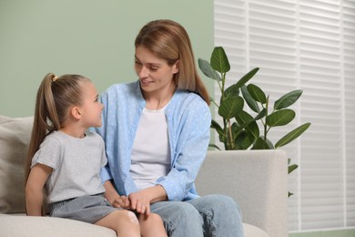 Photo of Mother applying ointment onto her daughter's knee on couch indoors