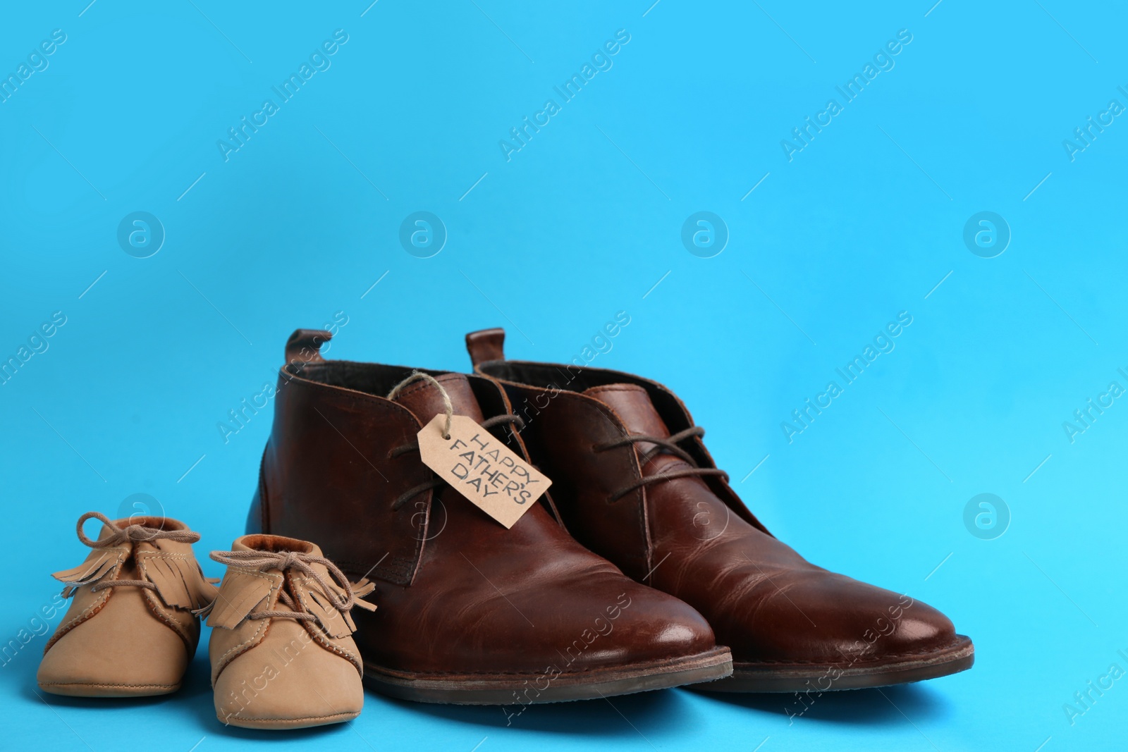 Photo of Dad and son's shoes on light blue background. Happy Father's Day