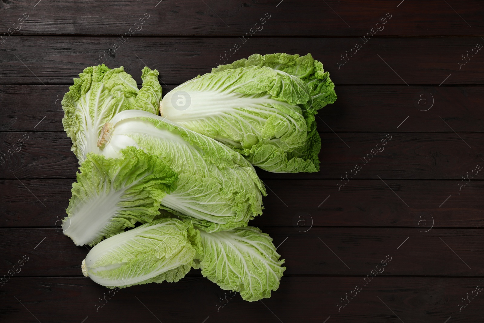 Photo of Fresh ripe Chinese cabbages on dark wooden table, fat lay. Space for text