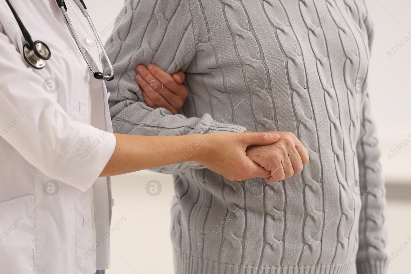 Photo of Nurse supporting elderly patient indoors, closeup view