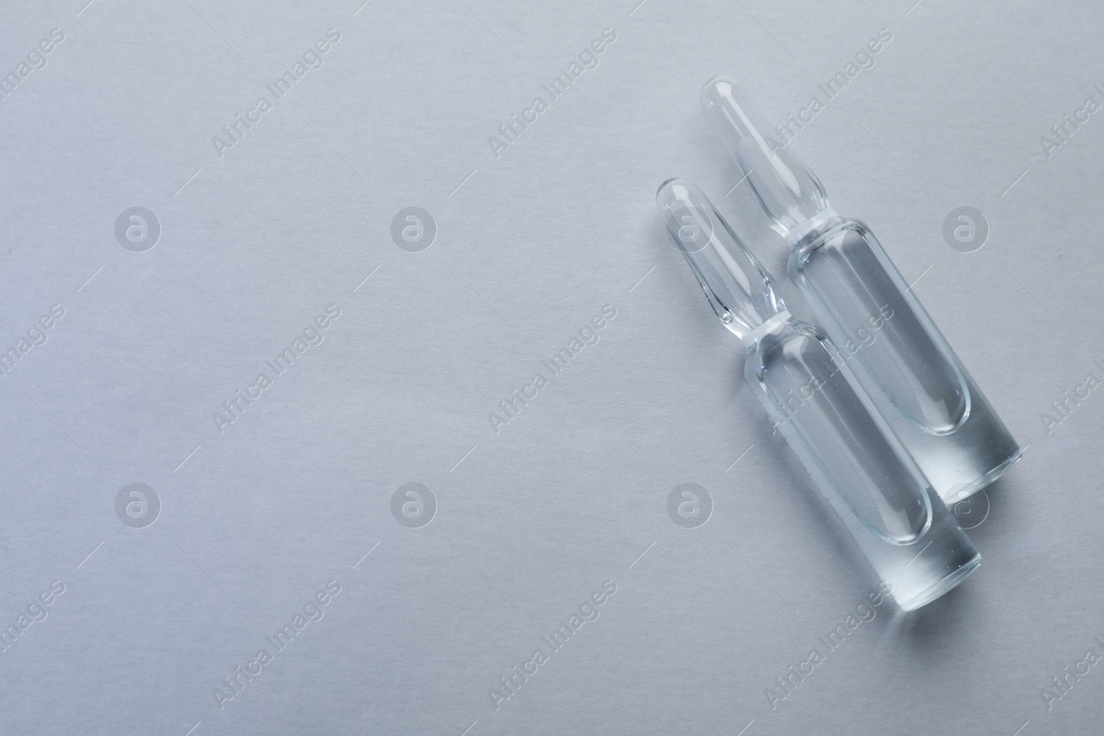 Photo of Pharmaceutical ampoules with medication on light background, flat lay. Space for text