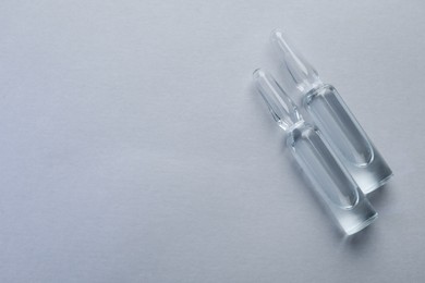 Photo of Pharmaceutical ampoules with medication on light background, flat lay. Space for text