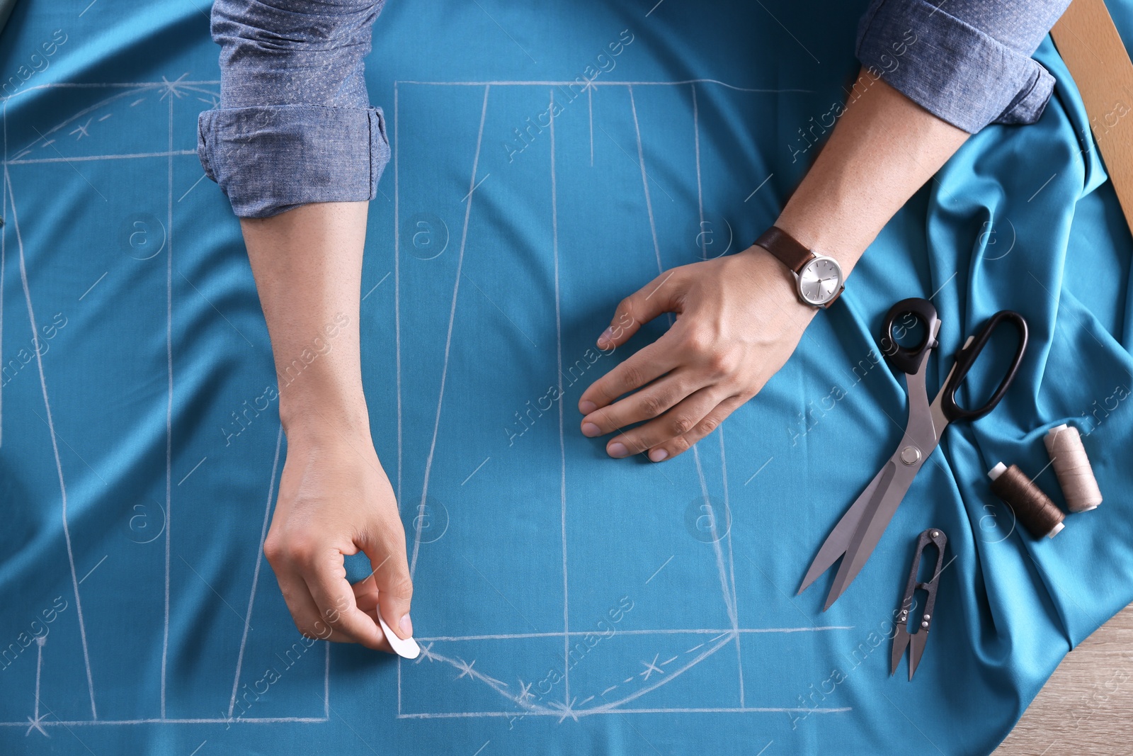 Photo of Tailor working at table in atelier, top view