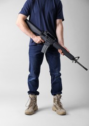 Photo of Assault gun. Man holding rifle on light background, closeup