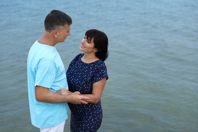 Happy mature couple spending time together on sea beach. Space for text