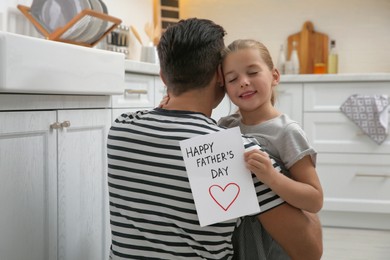 Photo of Little girl greeting her dad with Father's Day in kitchen