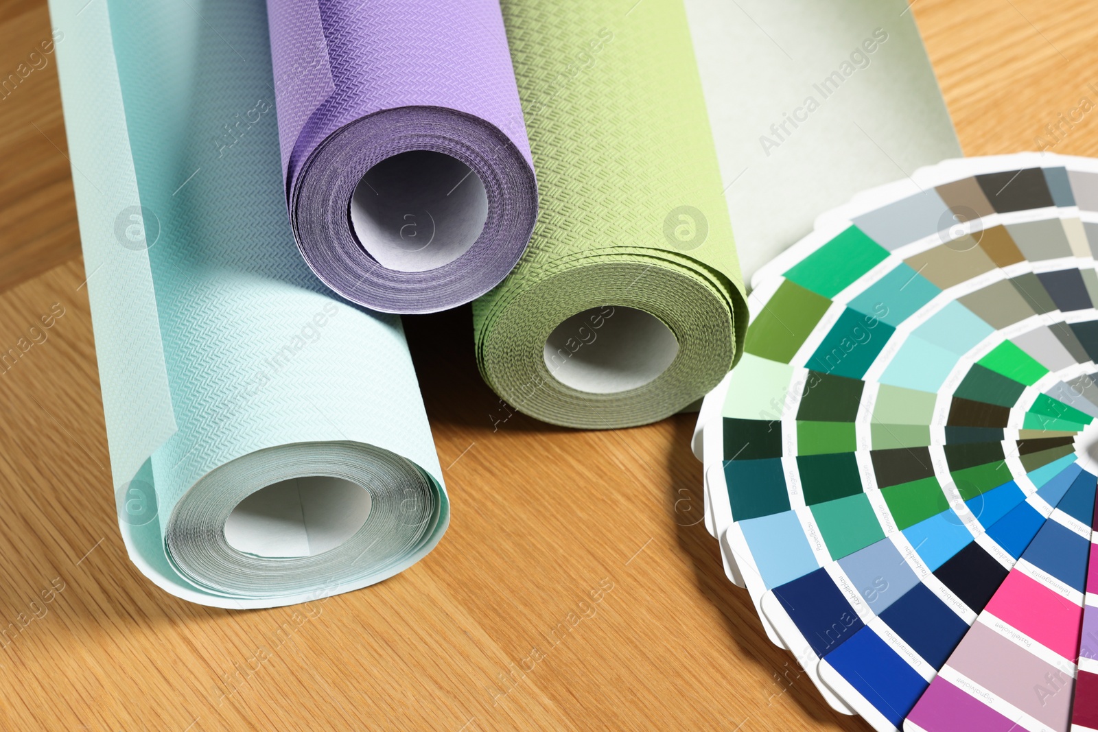 Photo of Different wallpaper rolls and color palette samples on wooden table