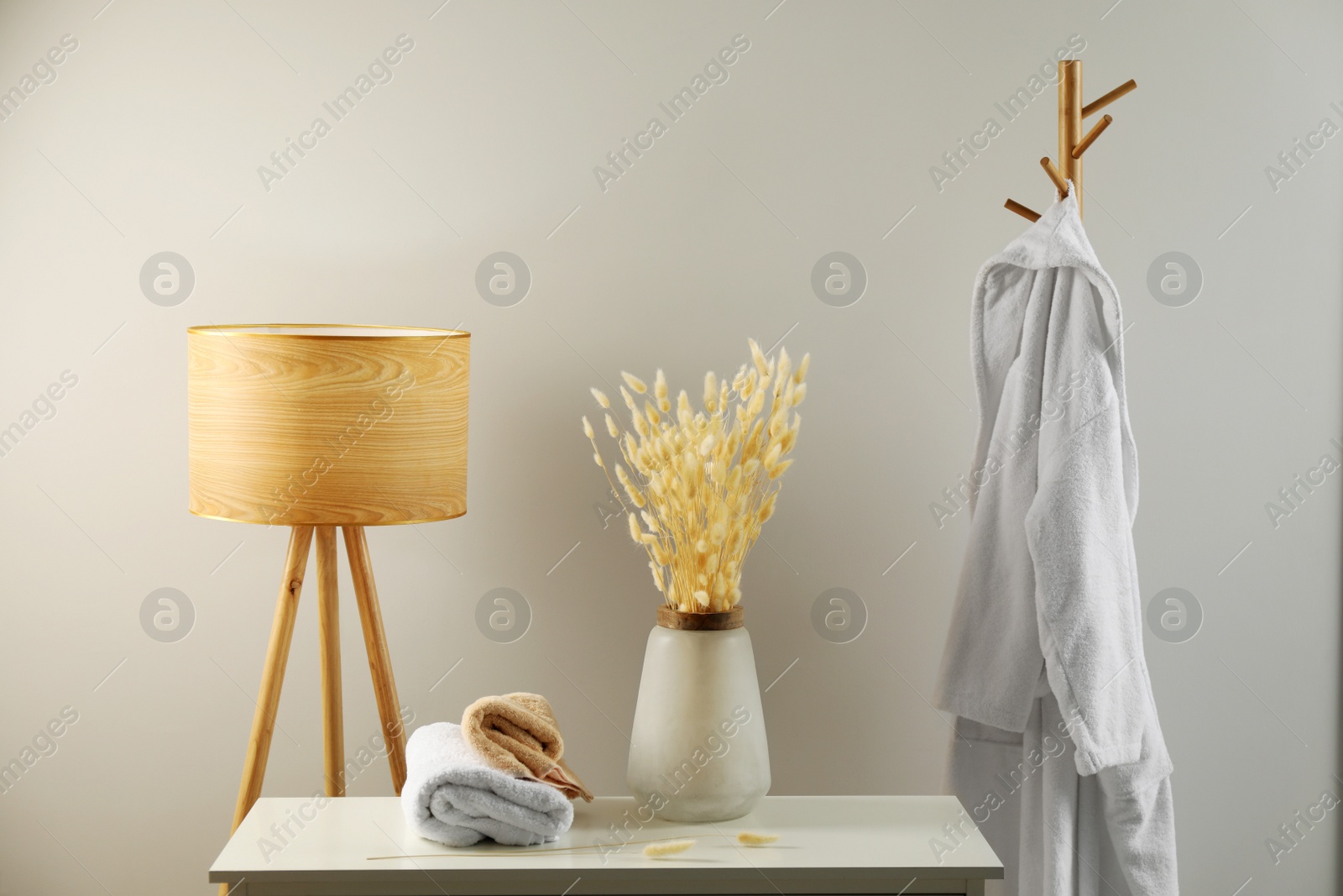 Photo of Floor lamp, hanger and chest of drawers near white wall