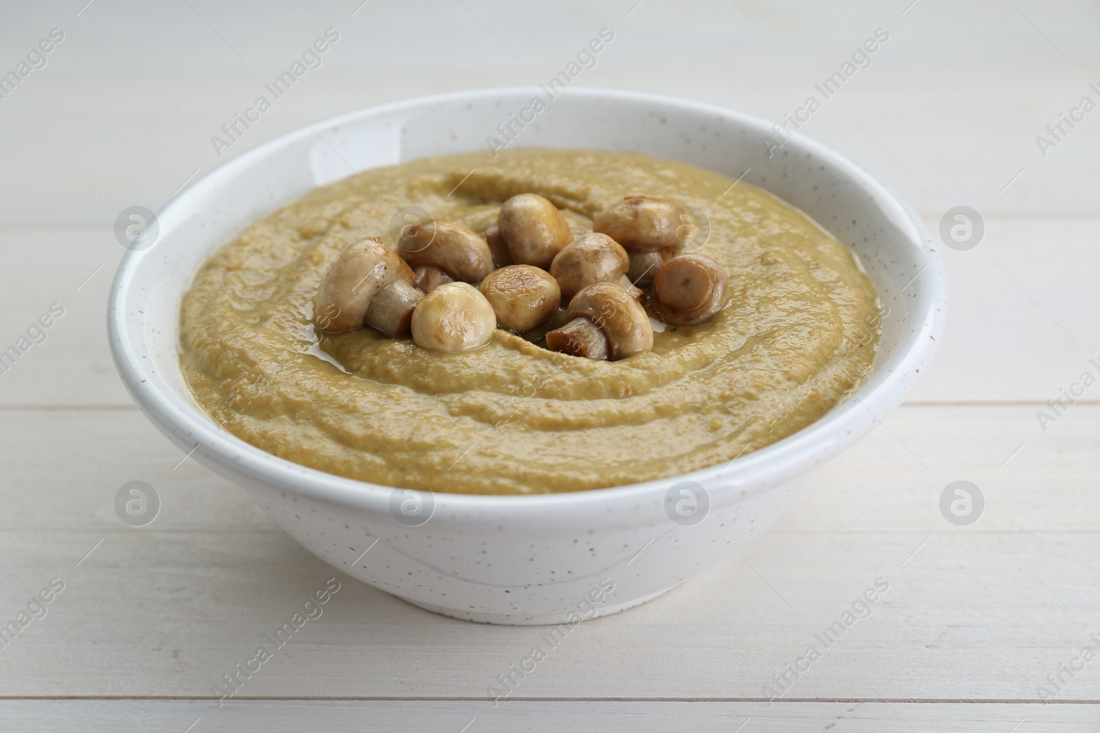 Photo of Delicious mushroom cream soup on white wooden table