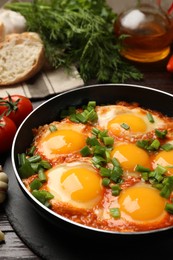 Delicious shakshuka in frying pan on wooden table, closeup