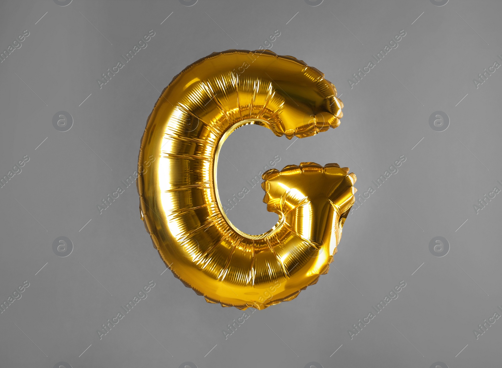 Photo of Golden letter G balloon on grey background