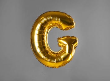 Photo of Golden letter G balloon on grey background