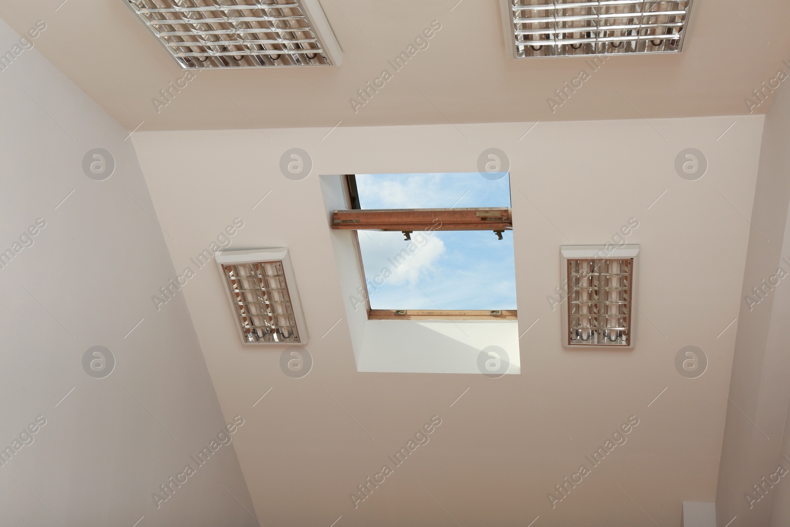 Photo of Open skylight roof window on slanted ceiling in attic room, low angle view