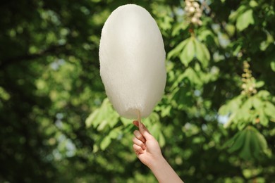 Woman holding sweet cotton candy outdoors, closeup