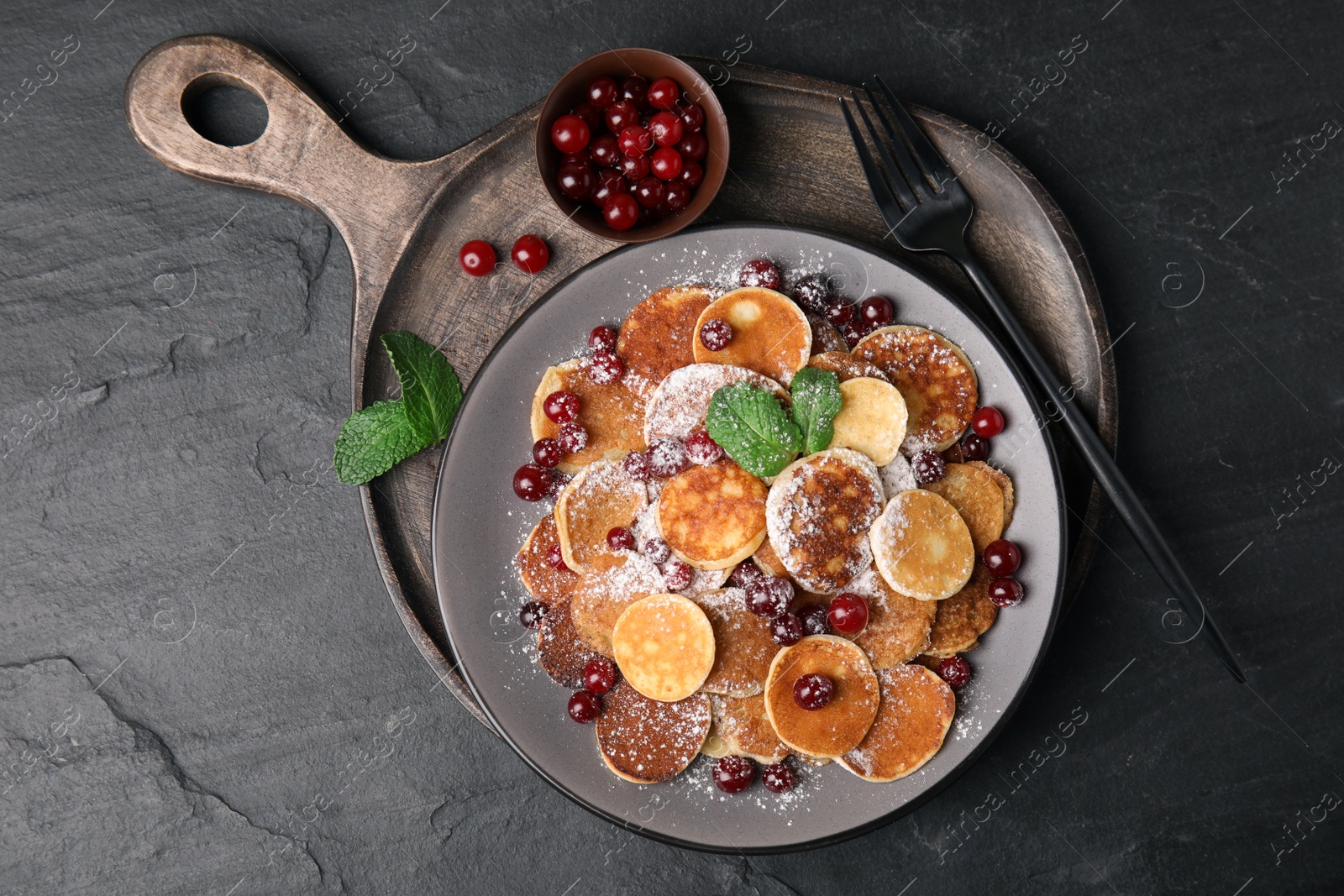 Photo of Cereal pancakes with cranberries served on black table, top view