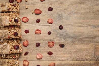 Tasty granola bars on wooden table, flat lay. Space for text