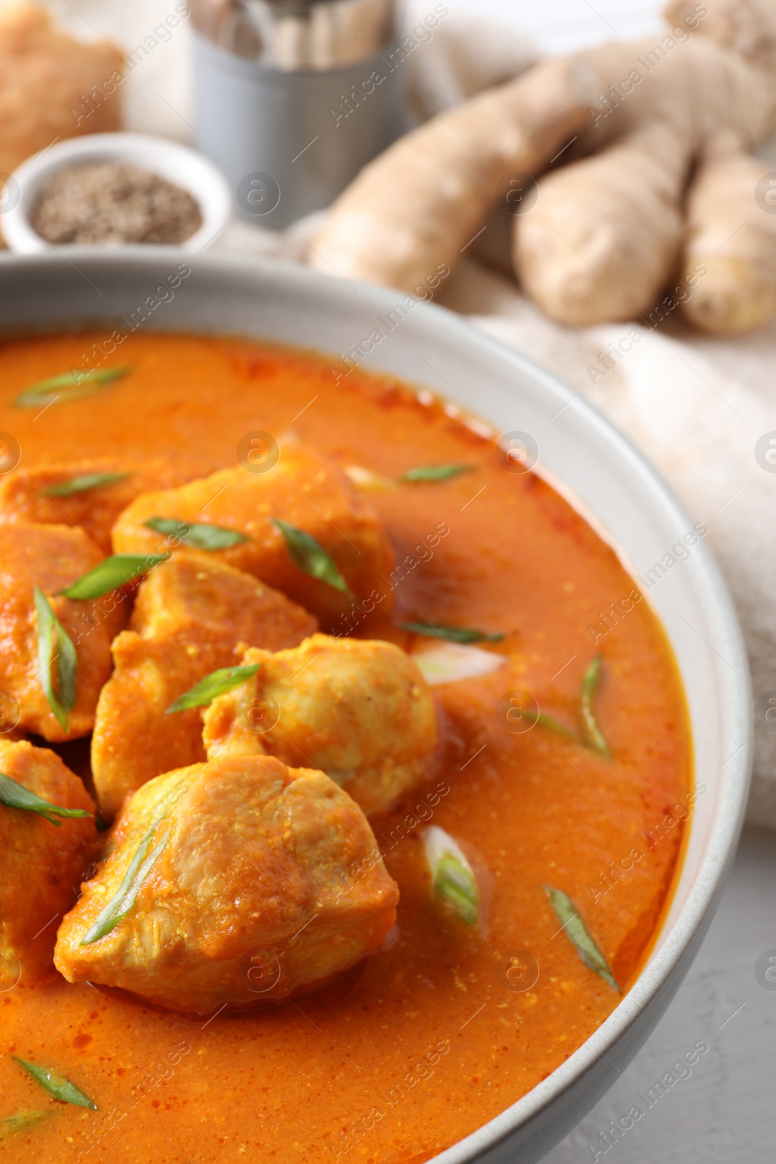 Photo of Bowl of delicious chicken curry on white table, closeup