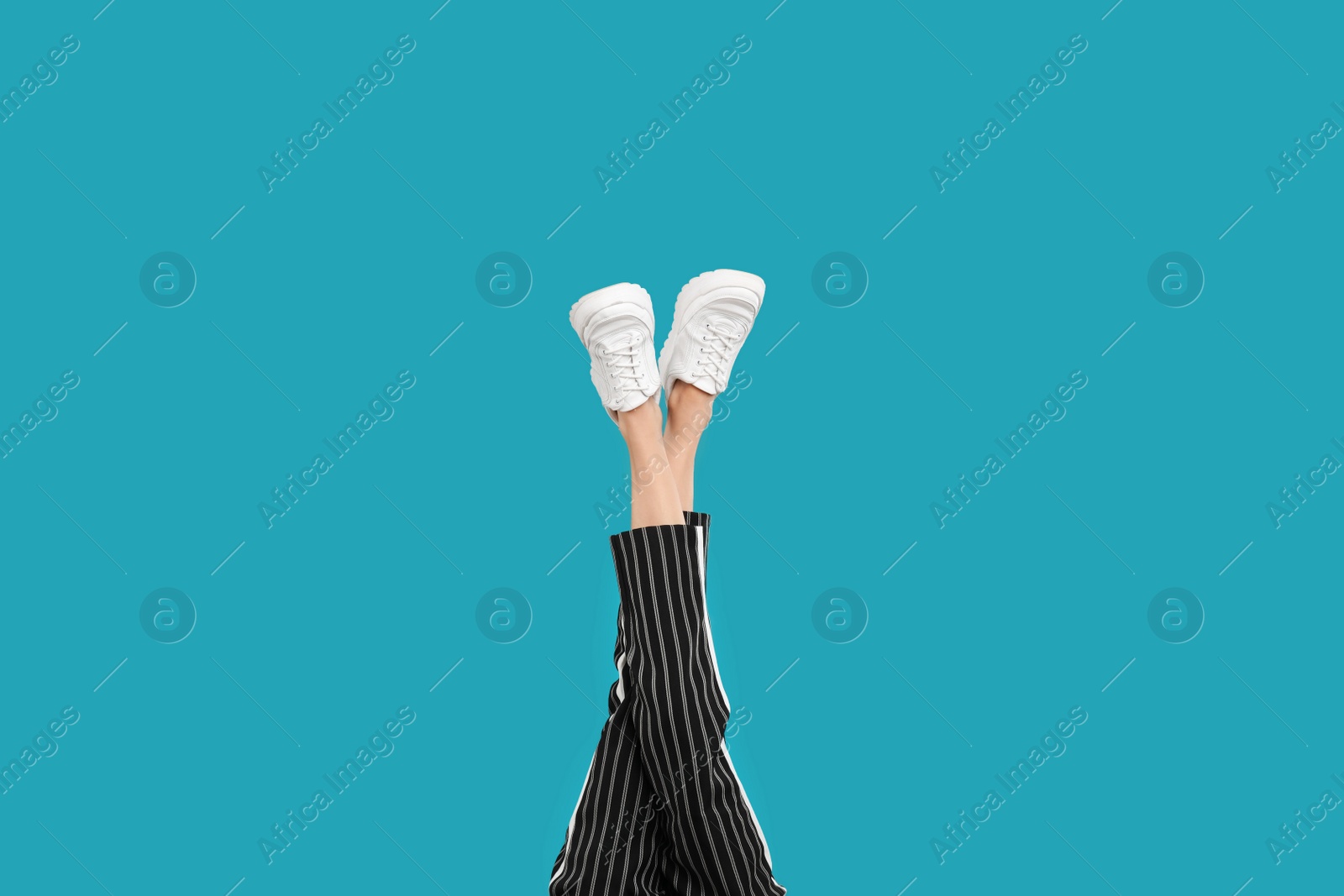 Photo of Woman in stylish sport shoes on light blue background