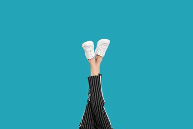 Photo of Woman in stylish sport shoes on light blue background