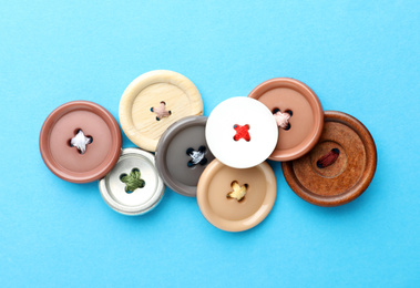 Photo of Many colorful sewing buttons on light blue background, flat lay