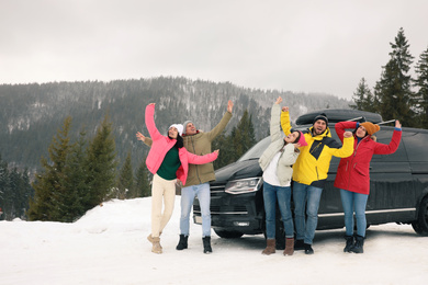 Happy people jumping near car on snowy road. Winter vacation