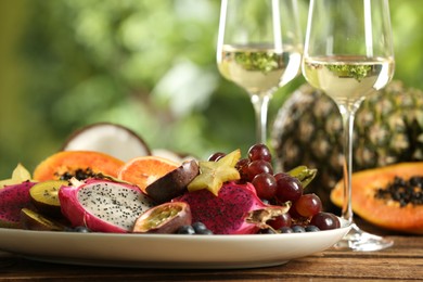 Photo of Delicious exotic fruits and wine on wooden table