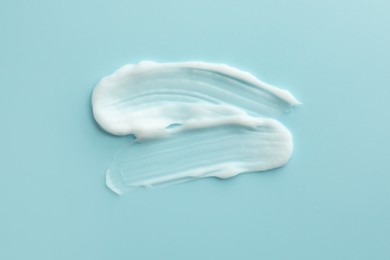 Photo of Samples of face cream on light blue background, top view