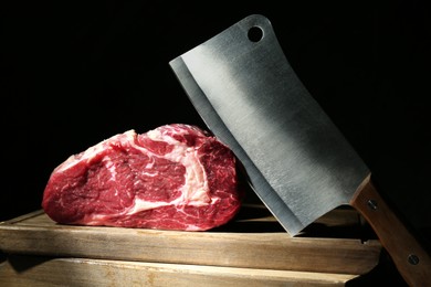 Photo of Piece of raw beef meat and knife on wooden board against black background