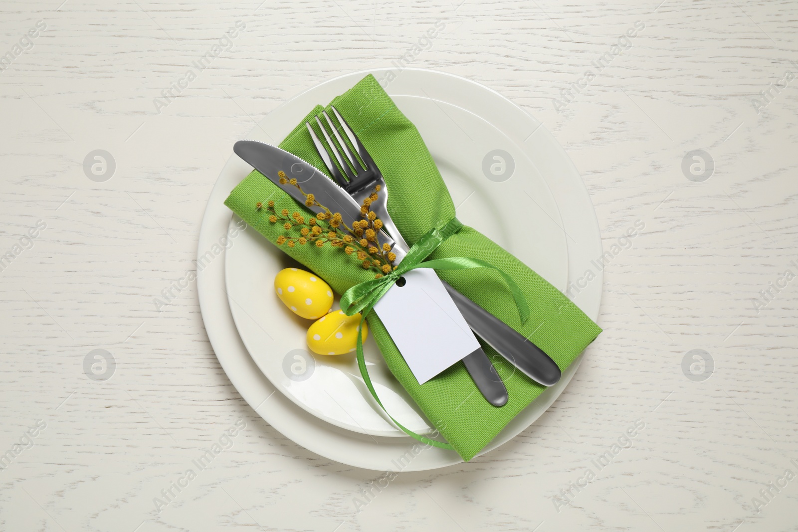 Photo of Festive Easter table setting with beautiful mimosa flowers and painted eggs, top view