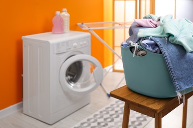 Photo of Laundry basket filled with clothes on bench in bathroom. Space for text