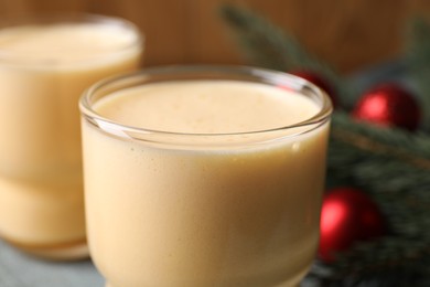 Glass of delicious eggnog on blurred background, closeup