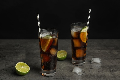 Photo of Refreshing soda drinks with straws on grey table against black background