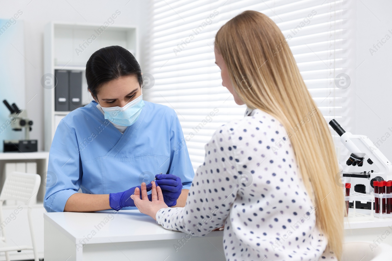 Photo of Laboratory testing. Doctor taking blood sample from patient at white table in hospital