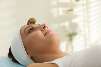 Photo of Young woman receiving snail facial massage in spa salon