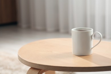 Photo of White mug on wooden table indoors. Mockup for design
