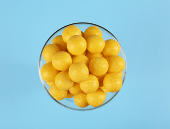 Photo of Tasty lemon drops in bowl on light blue background, top view