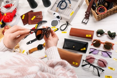 Photo of Woman holding glasses near table with different stuff, closeup. Garage sale