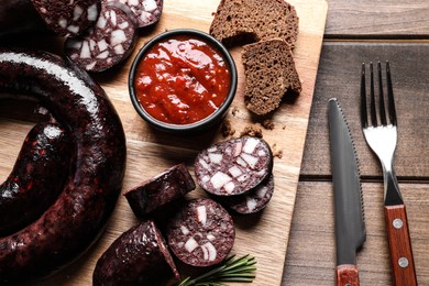 Photo of Tasty blood sausages served on wooden table, flat lay