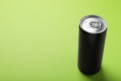Photo of Black can of energy drink on light green background. Space for text