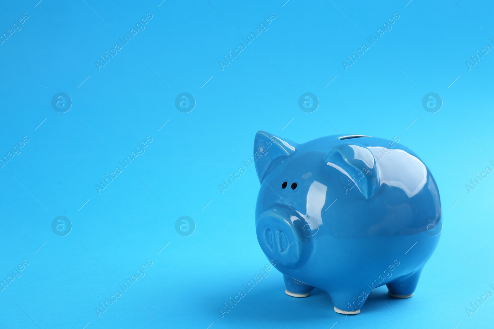 Photo of Piggy bank on blue background. Space for text