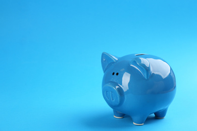 Photo of Piggy bank on blue background. Space for text