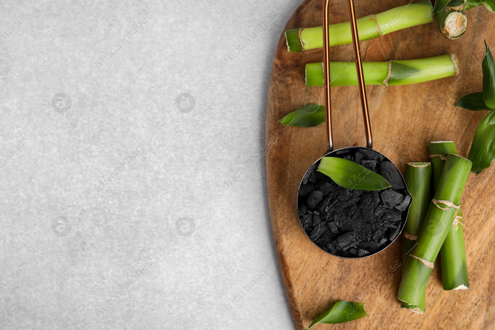 Photo of Fresh bamboo and charcoal on light gray table, flat lay. Space for text