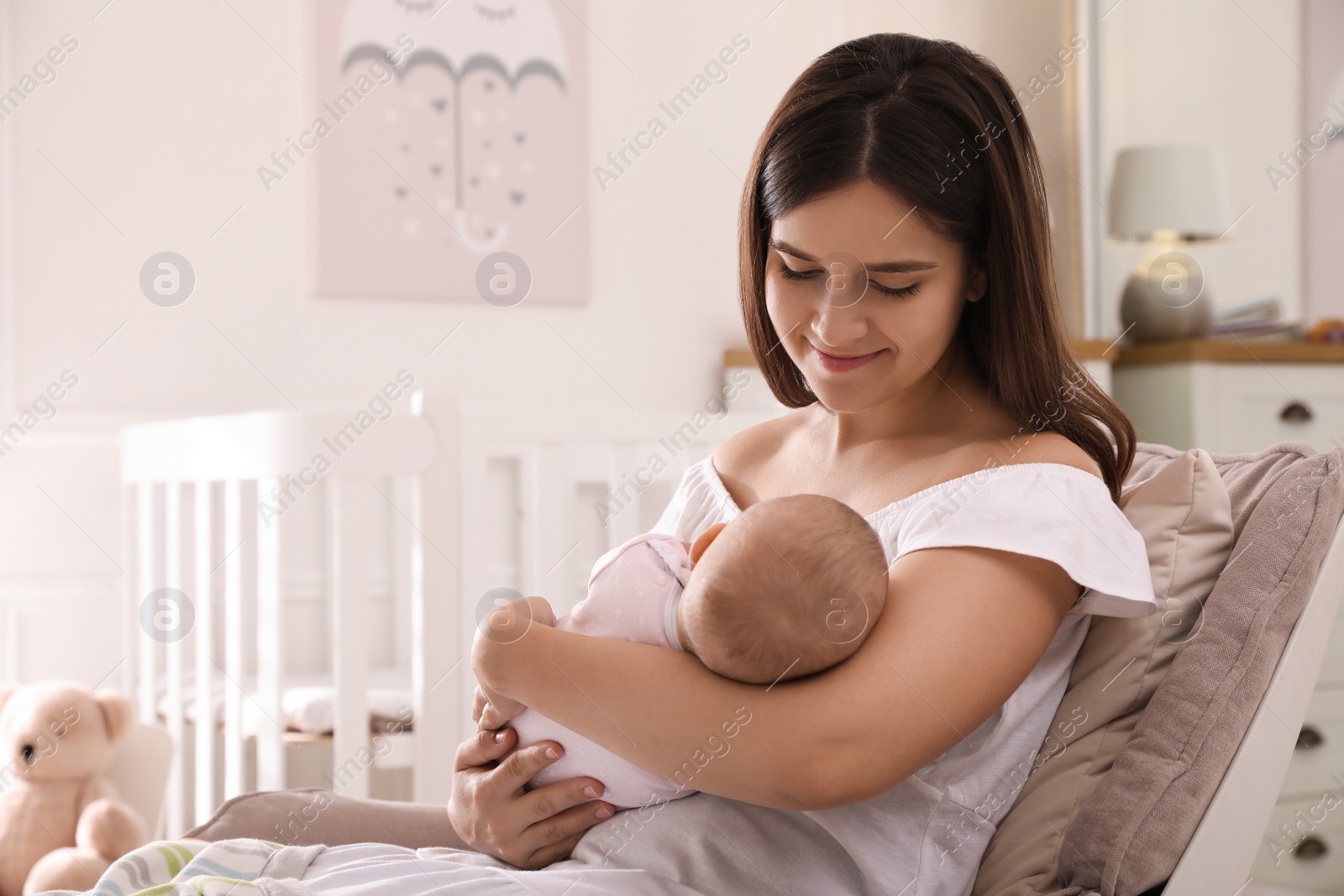 Photo of Happy young mother with her cute baby in armchair at home