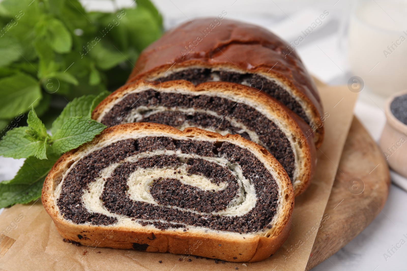 Photo of Cut poppy seed roll and mint on table, closeup. Tasty cake