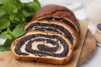 Photo of Cut poppy seed roll and mint on table, closeup. Tasty cake
