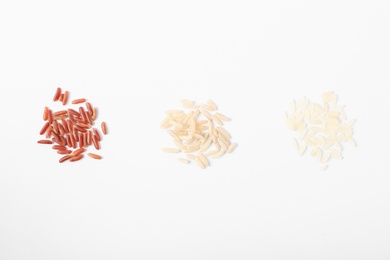 Photo of Different types of uncooked rice on white background, top view