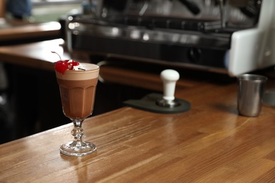 Photo of Glass of coffee drink with cherry and marshmallow on bar counter. Space for text